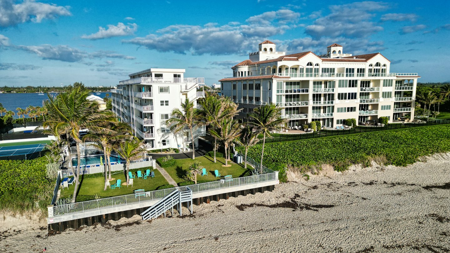 Luxury condos with terracotta roofs sit by a sandy beach.